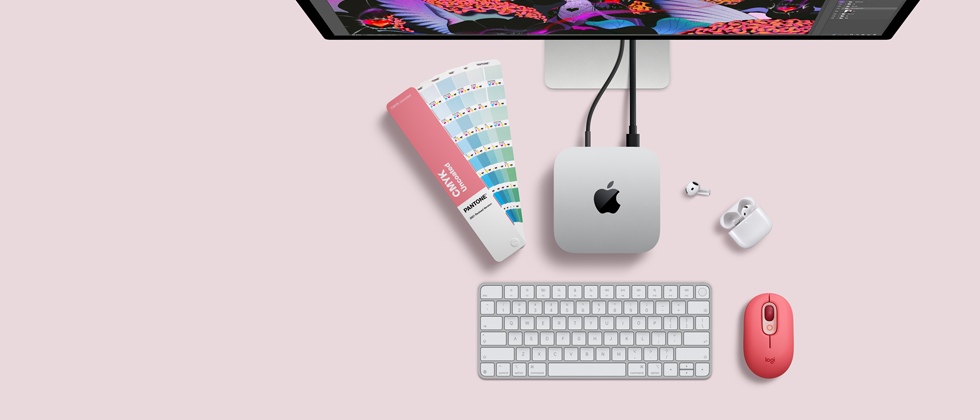 Mac mini, top, silver aluminum, rounded corners, glossy black Apple logo centered, connected by cord, Studio Display partially visible on top, AirPod 4, open, Pantone color swatches, and numeric keyboard and mouse