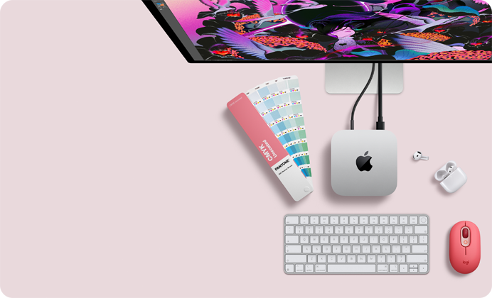 Mac mini, top, silver aluminum, rounded corners, glossy black Apple logo centered, connected by cord, Studio Display partially visible on top, AirPod 4, open, Pantone color swatches, and numeric keyboard and mouse